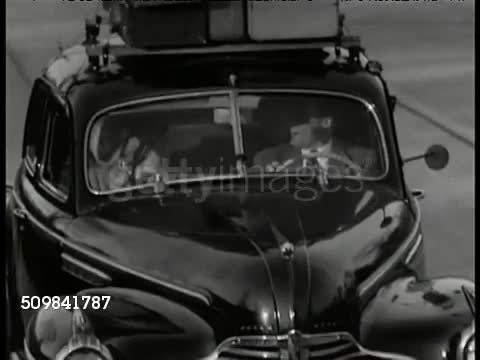 1946: U.S. VACATION: WS Two way highway, cars (outskirts of New York City). MS Americans driving in car w/ luggage on top. (POV car) Pulling into Motor Lodge Cabin parking lot, man putting up sign 'Open.' VS Driver & man talking. WS Car entering lot.